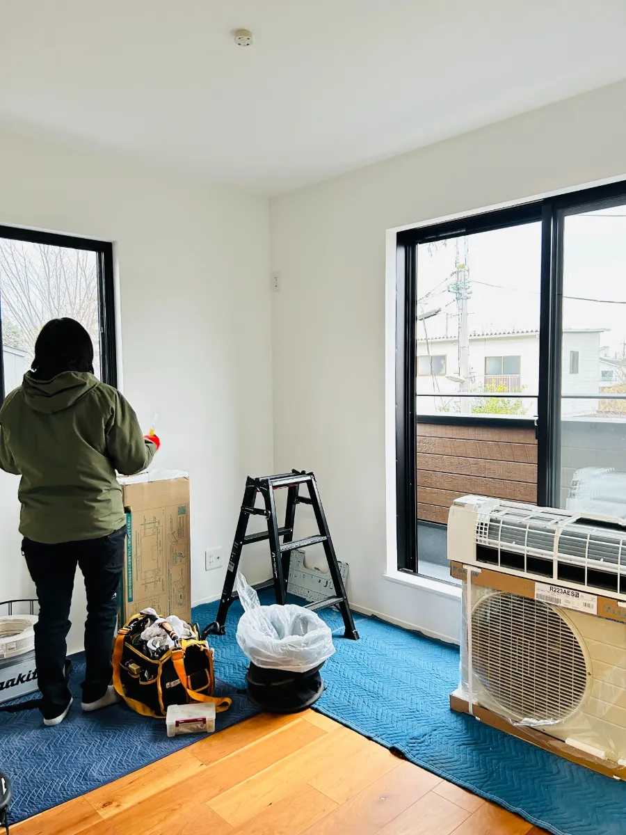 床を養生し、エアコンの取り付け準備をしている工事中の部屋の様子