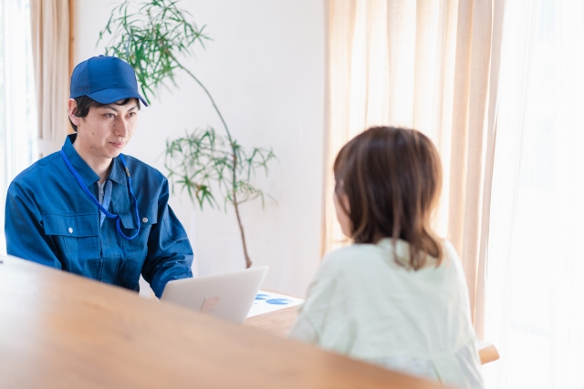 お客様の家で、ノートパソコンを見せながら説明する男性作業員