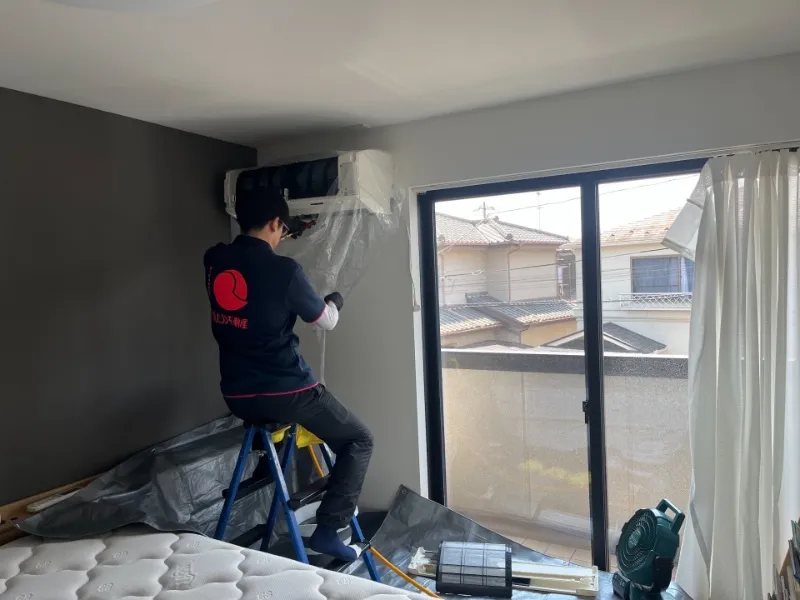 汚れたフィルターを確認しながら、エアコンの内部を点検する作業員