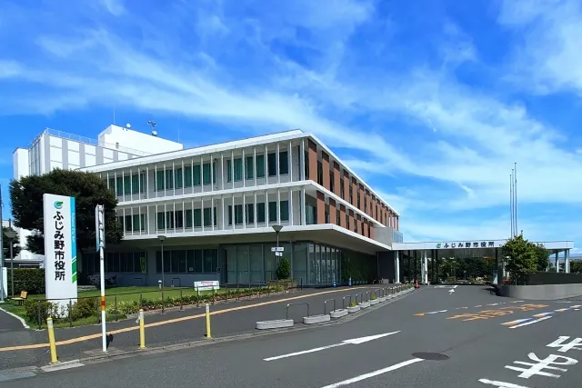 ふじみ野市役所の庁舎。青空を背景にしたモダンなガラス張りの3階建て建物
